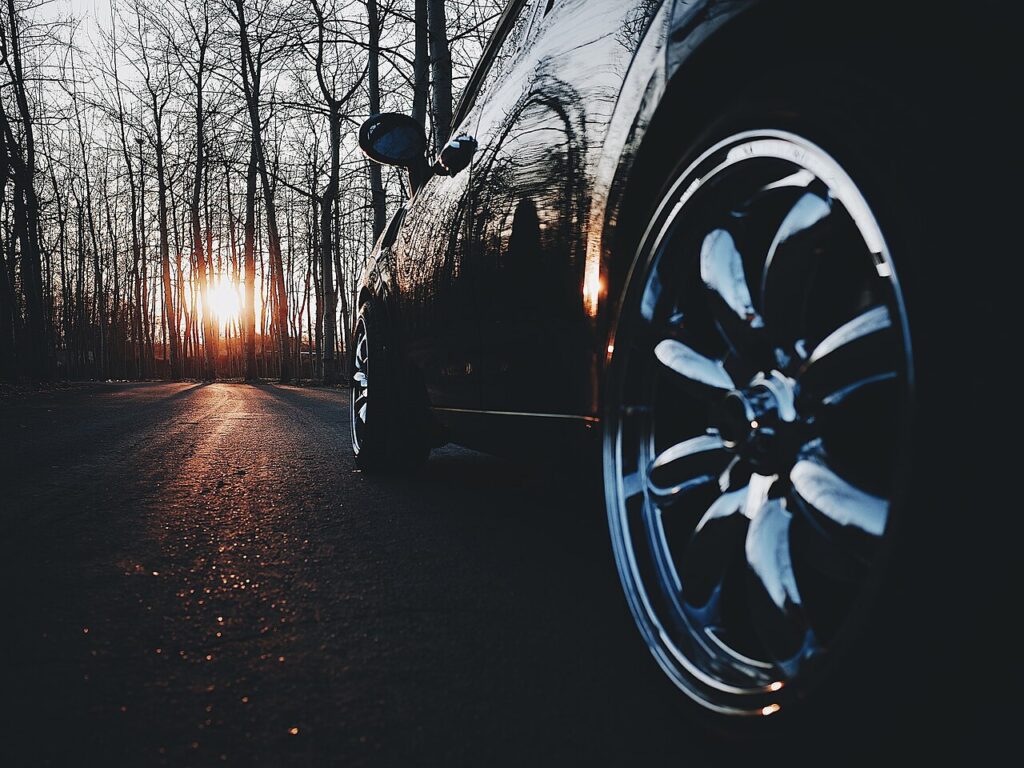 Roda cromada de um carro preto ao pôr do sol